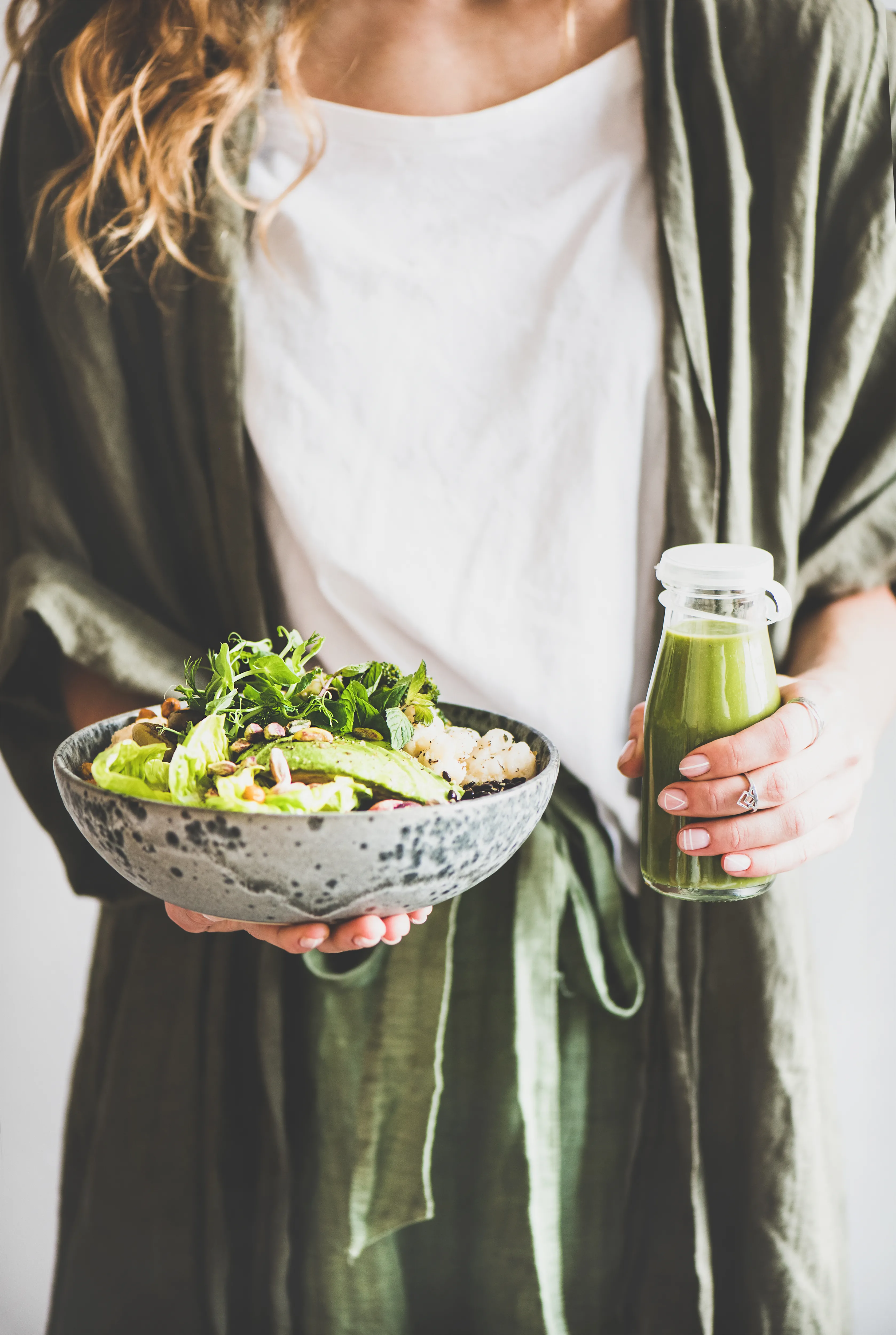 Frau hält grünen Salat und grünen Smoothie in den Händen